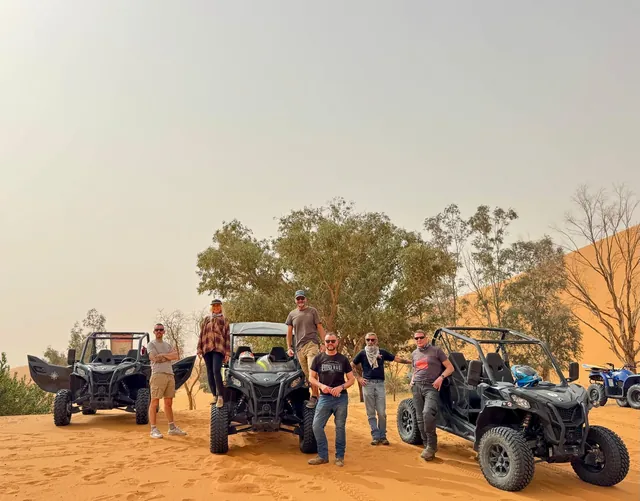 Guests standing beside Sahara buggies near the dunes